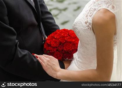 the bride and groom held hands and holding a red bouquet