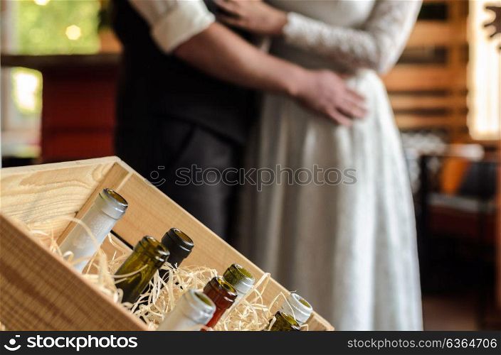 the bride and groom holding hands on the background of a wooden wall, bottle in the frame