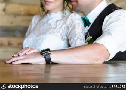 the bride and groom holding hands on the background of wooden wall
