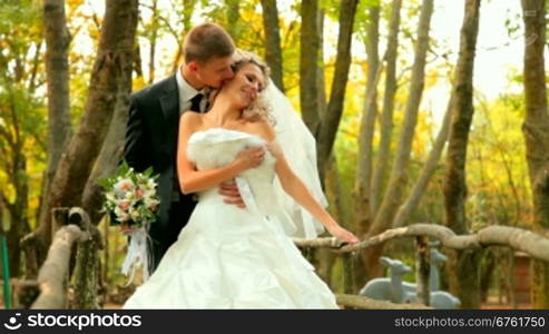 the bride and groom kissing in the autumn park