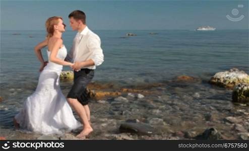 the bride and groom kissing on the beach in the background sailing ship