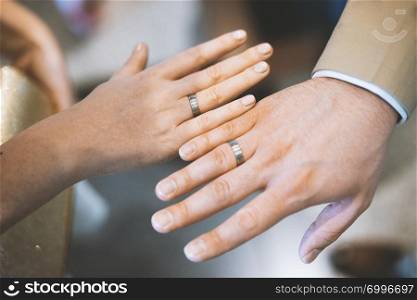 The bride and groom newlywed couple showing their hands with wedding rings