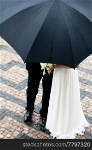the bride and groom with a bouquet of flowers under the umbrella