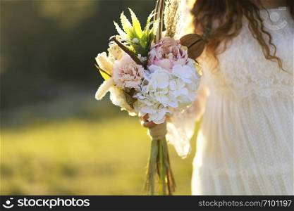 the bride and the flowers in her hand in outdoor
