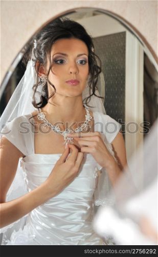 The bride before a mirror. The young girl in a wedding dress.
