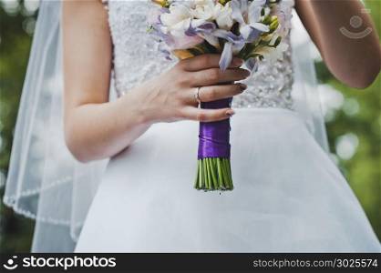 The bride holds a bunch of flowers.. Bunch of flowers in hands of the bride 2050.