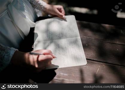 The bride holds a love letter. Wedding ceremony. The bride reads the wedding letter at the wedding ceremony.. The bride is holding a love letter. Wedding ceremony