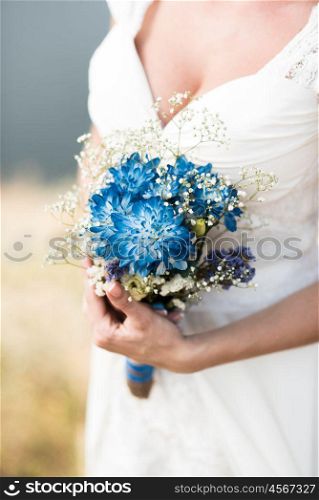 the bride holds a wedding bouquet with blue flowers