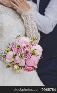 The bride holds the bouquet and the grooms hand.. The brides wedding bouquet of pink roses and peonies 2649.