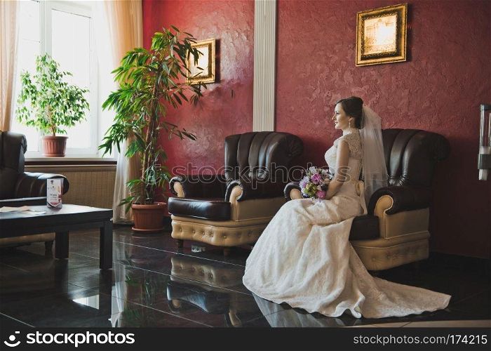 The bride in a gorgeous dress sits and waits.. The bride sits in a chair 3789.