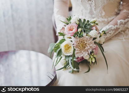 The bride in a lush white dress holding a bouquet of roses.. Bouquet of gorgeous flowers in womens hands 2392.