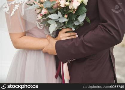 The bride in a pink dress with a bouquet stands in front of the groom.. The bride and groom stand opposite each other and hold a bouquet 2549.