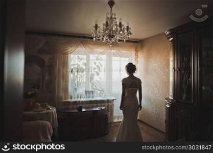 The bride in a wedding dress is by the window.. The bride about a light window 2302.. The bride about a light window 2302.