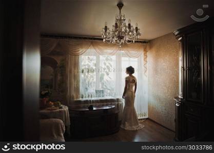 The bride in a wedding dress is by the window.. The bride about a light window 2304.. The bride about a light window 2304.