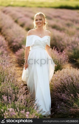 the bride in a white dress walks on the lavender field