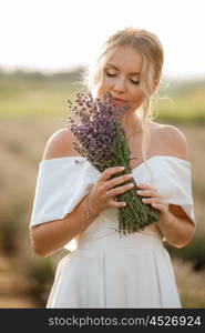 the bride in a white dress walks on the lavender field