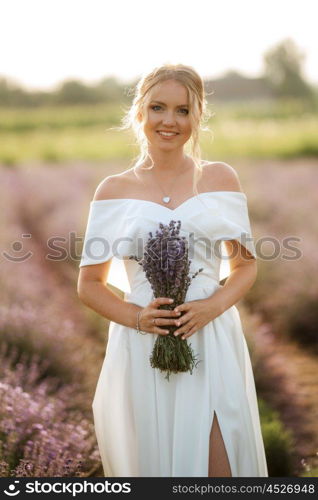 the bride in a white dress walks on the lavender field