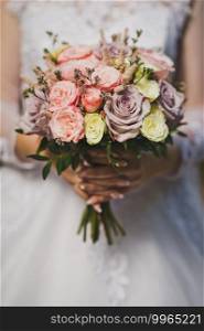 The bride is holding a bouquet of flowers.. Bouquet of flowers in the hands of the bride in a wedding openwork whi