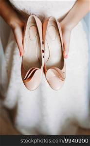 The bride is holding white shoes. Preparing for the wedding.. The bride is holding white shoes. Preparing for wedding.