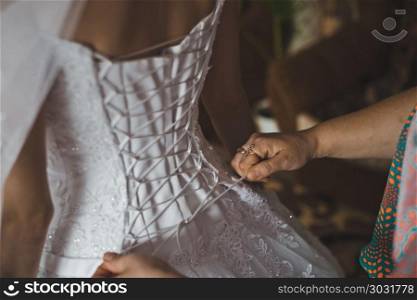 The bride lace up in a dress.. Process of clothing of a wedding dress 2352.. Process of clothing of a wedding dress 2352.