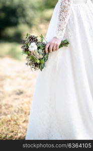 the bride&rsquo;s bouquet from cones and cotton close up in the hands of the bride lace dress forest backdrop