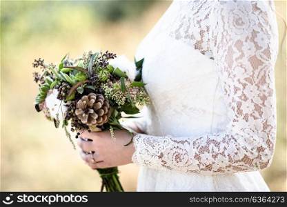 the bride&rsquo;s bouquet from cones and cotton close up in the hands of the bride lace dress forest backdrop