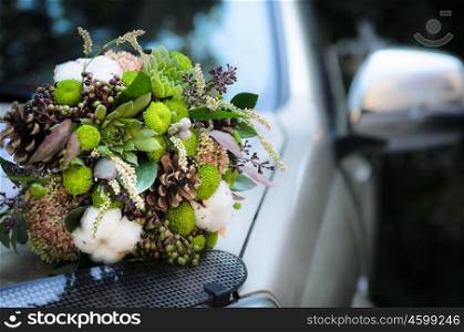 the bride&rsquo;s bouquet from cones and cotton on the hood of the wedding car