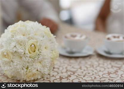 the bride&rsquo;s bouquet lying on the coffee table amid cups of coffee