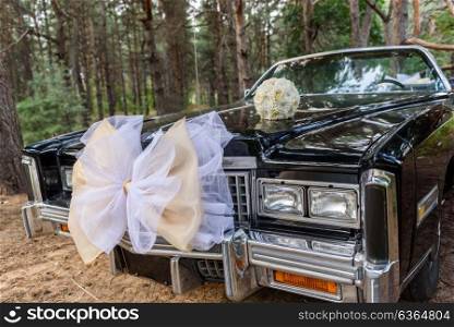 the bride&rsquo;s bouquet lying on the hood of the black car in the woods