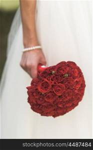the bride&rsquo;s bouquet of red roses in the hand of the bride, white dress