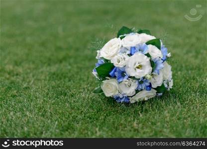 the bride&rsquo;s bouquet with blue flowers lying on a green lawn