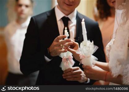 The bride&rsquo;s hand wears an engagement gold ring on the groom&rsquo;s finger. Wedding day. Hands with wedding rings. Close up.. The bride&rsquo;s hand wears an engagement gold ring on the groom&rsquo;s finger. Wedding day. Hands with wedding rings. Close up