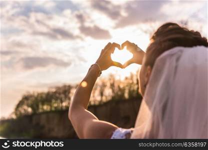 the bride shows a sign of heart at sunset