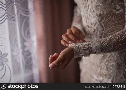 The bride, standing at the window, adjusts her lace sleeve.. The bride adjusts the lace sleeves of the dress 4263.
