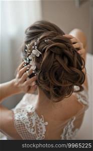 The bride touches her hair with her hands and adjusts the decoration on her head.. Beautiful bride hairstyle with beaded decoration 2502.