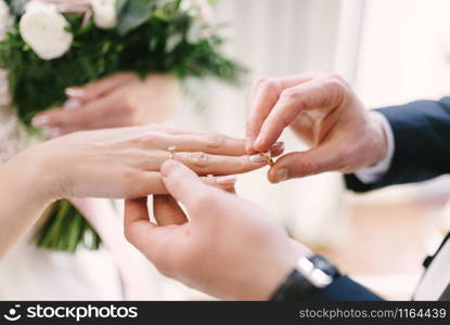 The bridegroom puts the wedding ring on the bride close up.. The bridegroom puts the wedding ring on the bride close up. The bride puts the bridegroom on the wedding ring.