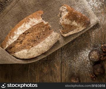 the broken loaf of bread on a cloth napkin and wooden boards, top view. loaf of bread top view