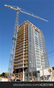 The building of a 26 floor high rise condominium with a large crane inOttawa Canada, under beautiful blue sky.
