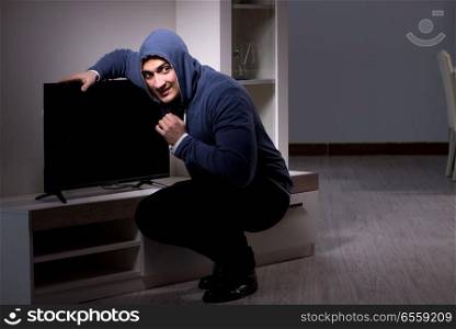 The burglar thief stealing tv from apartment house. Burglar thief stealing tv from apartment house