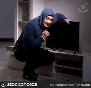 The burglar thief stealing tv from apartment house. Burglar thief stealing tv from apartment house