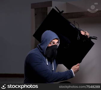 The burglar thief stealing tv from apartment house. Burglar thief stealing tv from apartment house