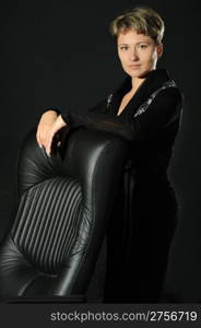 The business woman and armchair. A studio photo on a black background