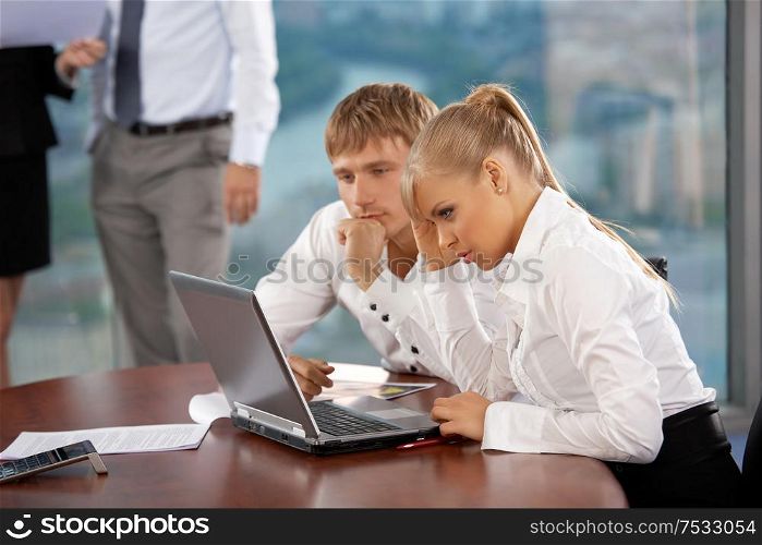 The business woman and business man look in the monitor at office