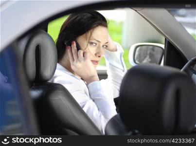 The business woman sits in the car and speaks by phone