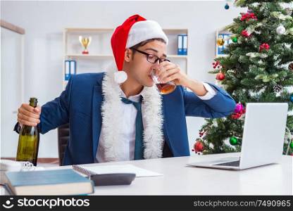 The businessman celebrating christmas holiday in the office. Businessman celebrating christmas holiday in the office