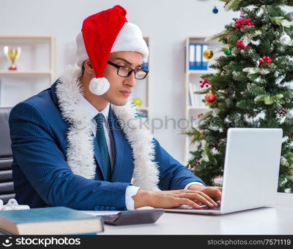 The businessman celebrating christmas holiday in the office. Businessman celebrating christmas holiday in the office