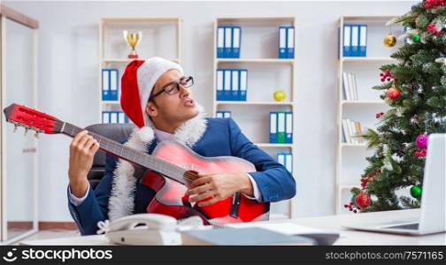 The businessman celebrating christmas holiday in the office. Businessman celebrating christmas holiday in the office