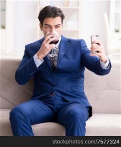 The businessman drinking wine sitting at home. Businessman drinking wine sitting at home