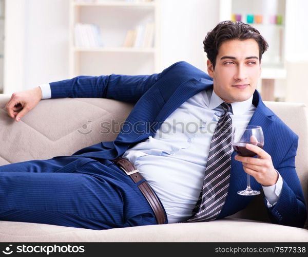 The businessman drinking wine sitting at home. Businessman drinking wine sitting at home