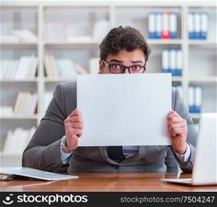 The businessman in office holding a blank message board. Businessman in office holding a blank message board
